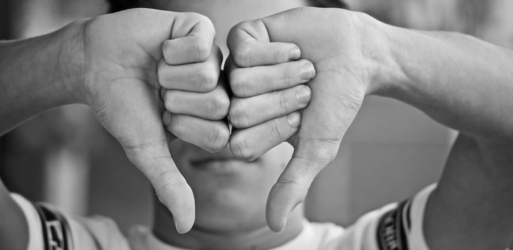 man holding his hands in front of his face with his thumbs down