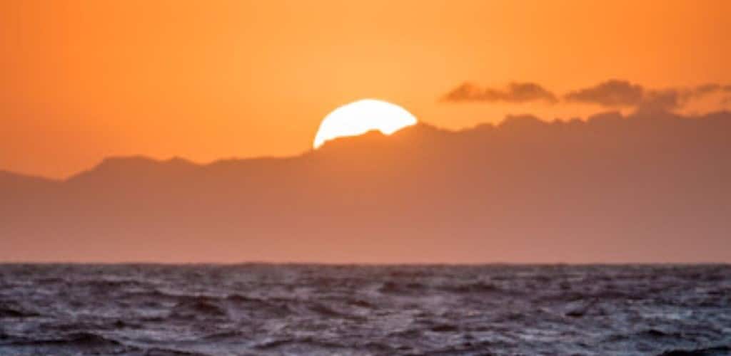 Image of a sunset in an orange sky with the sea in the foreground