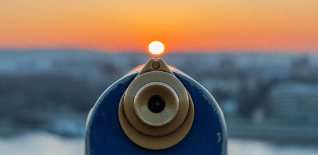 Photo of the lens end of a scope with a cityscape at sunset in the background