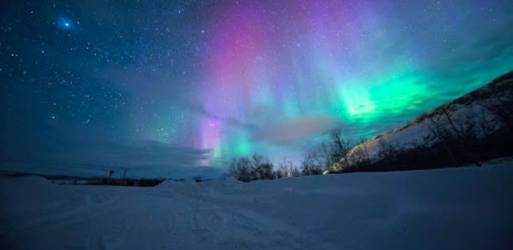 Night time snowy landscape with the Northern Lights and lots of stars in the sky