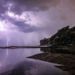 Photograph of a coastal scene with large dark clouds and lightning