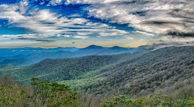 Image of rolling hillsides and a blue sky with fluffy clouds.